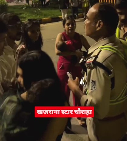 खजराना चौराहे पर पुलिस अधिकारी से बहस करतीं गर्भवती महिला और उनके परिजन; महिला की गोद में नवजात बच्चा स्पष्ट रूप से दिख रहा है।